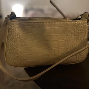Vit axelväska med krokodilmönster - Snygg beige axelväska med krokodilmönster och dragkedja. Använd mycket men bra skick!
