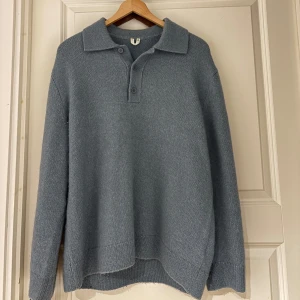 Blå stickad tröja med krage - Säljer en stilren blå/grå stickad tröja med krage och knappar framtill. Perfekt för kyligare dagar med sin mjuka och bekväma passform. Ett måste i garderoben för en klassisk look. (Storlek S, men sitter större).