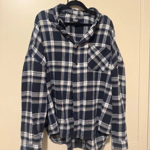 Blå och vit rutig skjorta herr - Snygg blå och vit rutig skjorta med klassisk krage och bröstficka. Perfekt för en avslappnad stil. Skjortan har långa ärmar och knappar framtill. Mjuk skjorta ( använt endast några gånger Ordpris 300kr )