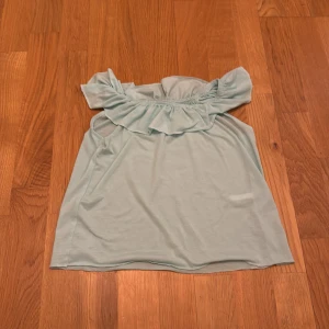 Ljusblå offshoulder topp från H&M - Säljer en söt och tunn ljusblå offshoulder topp från H&M med volangdetaljer runt axlarna.  Den är storlek 98-104 men passar 128-130. 💕
