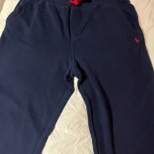 Mörkblå mjukisbyxor från Polo Ralph Lauren - Säljer ett par mörkblå mjukisbyxor från Polo Ralph Lauren med röd logga på sidan. Fint använt skick. Strl 