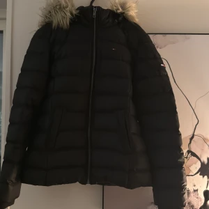  Vinterjacka  - Säljer en marinblå vinterjacka från Hilfiger Denim med pälskantad huva och dragkedja. Jackan har en klassisk design med långa ärmar och är perfekt för kyliga dagar. Den har små logodetaljer på bröstet och ärmen. Storlek M