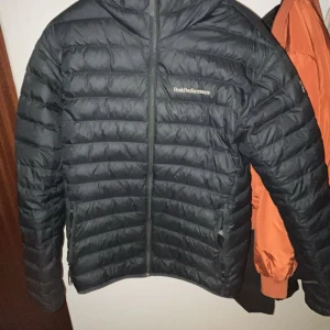 Svart dunjacka från Peak Performance - Säljer en stilren svart dunjacka från Peak Performance. Jackan har en praktisk dragkedja och är quiltad för extra värme. Perfekt för kyliga dagar.