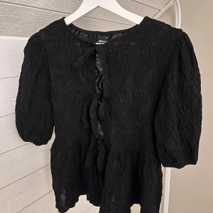 Topp med rosetter - Fin topp med tre rosetter och puffig arm. Perfekt till en festligare look! Använd fåtal gånger. Pris kan diskuteras!