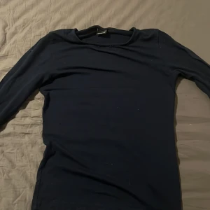 Mörkblå långärmad tröja från Gina Tricot - Säljer en stilren mörkblå långärmad tröja från Gina Tricot. Perfekt för en enkel och bekväm look. Tröjan har en klassisk passform och är tillverkad i ett mjukt material.