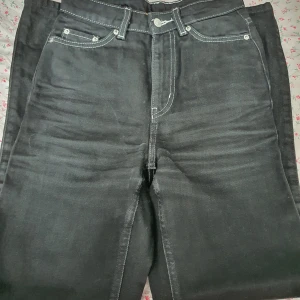 Svarta jeans från Weekday - Snygga svarta jeans från Weekday med kontrasterande vita sömmar.  Lite sliten på vissa ställen men inget som syns.