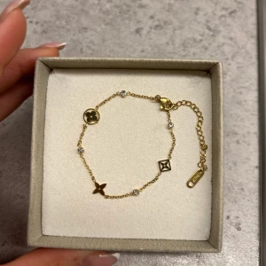 Guldarmband med symboler - Elegant guldarmband med små symboler och gnistrande detaljer. Armbandet har en justerbar kedja. 18k guld pläterad i rostfritt stål 