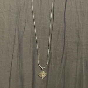 Silverfärgat halsband med träd-hänge - silverfärgat halsband med ett träd-hänge. Hänget har en unik design med ingraverade detaljer. 