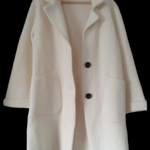 Härligt varm och snygg jacka/kappa i Off-white. Helt ny. One size. Garoff. - Härligt mjuk och varm kappa/jacka av märke Garoff. Direkt från butiken, nypris 1 600 kronor. Passande både till vardags och fest. Bröstvidd 53 cm, (fr armhåla till armhåla). Längd, 93 cm (mätt från axel).
