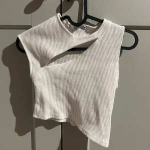 Vit ribbad topp från Zara - Snygg vit ribbad topp från Zara. Snygg asymmetriska design. Passar bra till både jeans och kjol. Använd endast 1-2 gånger.