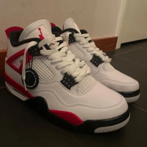 Nike Air Jordans i vitt och rött - Snygga Nike Air Jordans i vitt med röda och svarta detaljer. Skorna har klassisk snörning och en ikonisk design med Jumpman-loggan på plösen. Perfekta för sneakerheads som vill ha stil och komfort. Säljer dom för 1000 men billigare funkar!