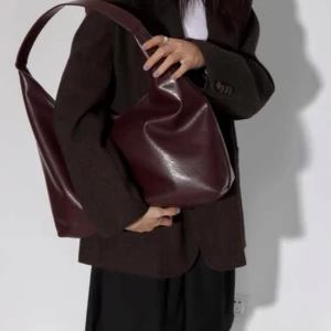 Brun axelväska  - Snygg och stilren brun axelväska i skinnimitation. Väskan har en bred axelrem och en dragkedja för säker förvaring. Perfekt skol/ jobbväska med plats för dator och böcker. Lite sliten på axelremmen (se bild 5). Kan mötas upp vid Odenplan