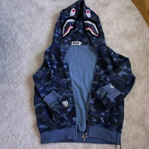 Blå bape hoddie  - Tja! Säljer en blå camo bape hoddie, Koftan passar både för tjejer och killar, tröjan håller dig varm nu runt vintern. De är storlek S men passar även Xs om du har några funderingar om tröjan är de bara att kontakta mig😊. Priset kan alltid diskuteras vid en snabb affär👍!