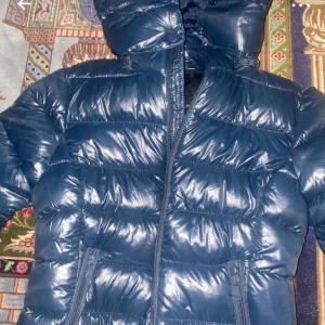 Blå pufferjacka med huva - Snygg blå pufferjacka med huva och dragkedja. Perfekt för kyliga dagar med sin vadderade design. Jackan har praktiska fickor framtill.