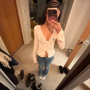 Rosa långärmad knytblus - Säljer en stilren ljus rosa långärmad blus med knytning framtill. Perfekt för en chic och avslappnad look. Blusen har en v-ringad design och är tillverkad i ett mjukt material. Nypris 300