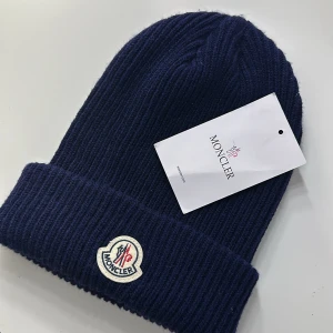 Mörkblå stickad mössa från Moncler - Snygg mörkblå stickad mössa från Moncler med ribbad design och broderad logotyp framtill. Perfekt för vintern kan gå ner i pris 🤍