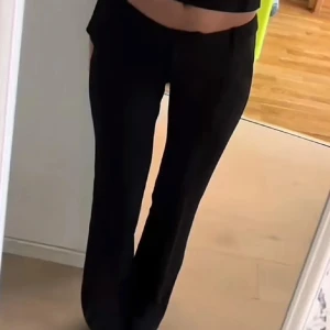 Svarta kostymbyxor - Snygga svarta kostymbyxor med låg midja och bootcut-stil. Perfekta för en stilren look. Byxorna har en klassisk design med hällor för bälte och diskreta fickor. De är helt nya och säljer då de inte passar mig. De är långa och passar mig i längden som är 175 cm