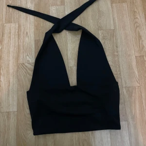 Svart halterneck topp från Shein - Snygg svart halterneck topp från Shein. Perfekt för en kväll ute eller en avslappnad dag. Toppen har en stilren design med knytband runt nacken.