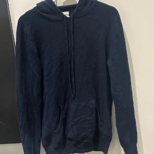 Mörkblå hoodie  - Säljer en stilren mörkblå hoodie från john Henric med känguruficka och justerbar huva. Perfekt för kyliga dagar och avslappnade stunder. Passar både till jeans och träningsbyxor. Storlek M, pris kan diskuteras. 