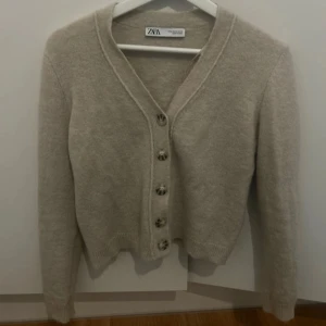 Beige kofta från Zara - Säljer en stilren beige kofta från Zara med knappar framtill. Den är i strl M men liten i strl. Koftan har en klassisk design med långa ärmar och är perfekt för kyligare då den är av ullmix 💗pris kan diskuterad vid snabb affär
