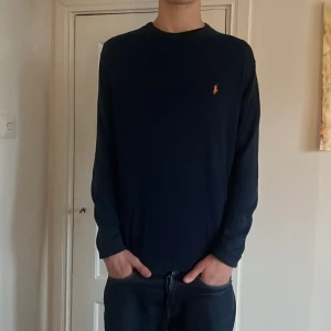 Mörkblå tröja från Ralph Lauren - Säljer en stilren mörkblå tröja från Ralph Lauren med det klassiska logotypbroderiet på bröstet. Tröjan är tillverkad i en mjuk blandning av bomull och kashmir, vilket gör den både bekväm och lyxig. Perfekt för en avslappnad men elegant look. Modellen är 185 och väger 65kg