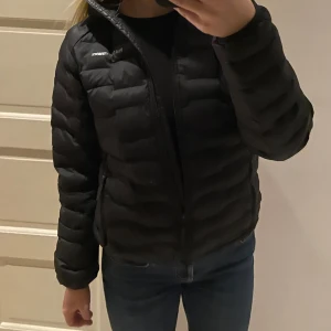 Svart jacka från PeakPerformance - Säljer en svart pufferjacka från PeakPerformance med huva och dragkedja. Jackan är i storlek M men passar bra på mig som annars är S. Jackan är välanvönd och därför säljer jag den billigt, den har blivit lappad på ryggen och även på höger ärm men går utmärkt att använda trots det. Kontakta för fler bilder😊 Nypris för jackan var närmare 200€