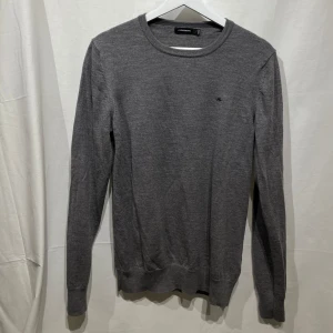 Grå tröja från J.Lindeberg - Snygg grå tröja från J.Lindeberg med rund hals och diskret logga på bröstet. Perfekt för en stilren look. Tröjan är storlek L men passar bättre på M. Modellen är 180cm