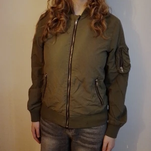 Grön Jacka - Tunn grön jacka från H&M i storlek 152. Kedjan är lite trög men kan troligen fixas. Katt finns I hemmet