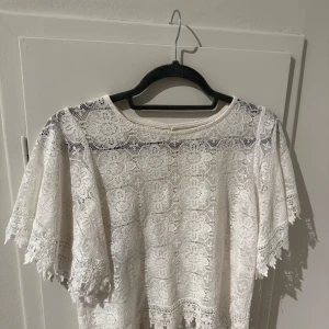 Vit spetsblus - Säljer en vacker vit spetsblus med blommigt mönster. Blusen har korta ärmar och en rund halsringning. Perfekt för en somrig look eller en speciell tillställning💕//Passar XS/S💗