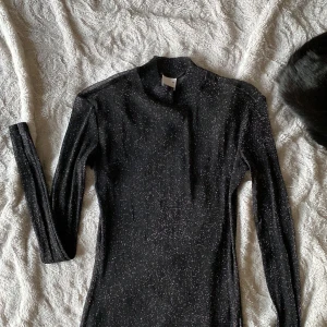 Svart glittrig topp från Gina Tricot - Säljer en svart glittrig topp från Gina Tricot i storlek XS. Har långa ärmar, materialet är transparent och passar perfekt att ha en snygg bralette under. Perfekt för en utekväll eller nyårsfirandet. Använd 1 gång. Storleken passar även en M. Jag va vanligtvis en M på bilden.