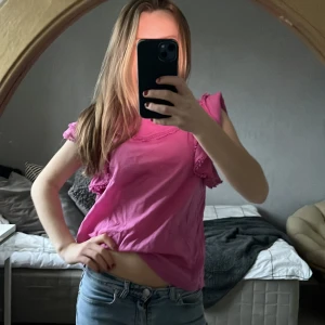 Rosa blus med spetsdetaljer - Säljer en söt rosa blus med spetsdetaljer och volanger. Blusen har korta ärmar och en lös passform, perfekt för vår och sommar. Den är gjord i ett lätt och bekvämt material. Toppen är från mango i strl M men passar mig som har xs/s! Så fin men kommer inte till användning🩷🩷