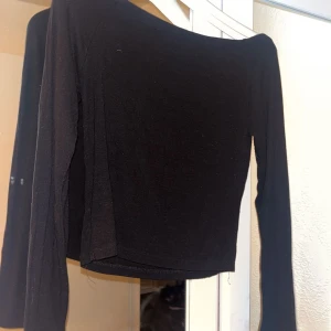 Svart offshoulder topp - Snygg svart offshoulder topp med långa ärmar. Perfekt för en stilren look. Toppen är croppad och använd fler gånger men fortfarande i bra skick