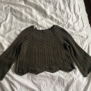 Olivgrön stickad tröja från Only🫒 - Säljer en olivgrön stickad tröja med ett vackert hålmönster. Tröjan har långa ärmar och en croppad passform som ger en trendig look. Perfekt för lager-på-lager under höst och vår.