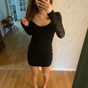 Svart spetsklänning - Snygg svart spetsklänning från H&M Divided med långärmad design och en tight passform. Klänningen har en v-ringad hals och är ganska kort. Jag tycker att det är fint att den har ett blommönster i spetsmaterial vilket syns tydligare på armarna än resten av klänningen. Materialet är hyfsat stretchigt💗💗💗