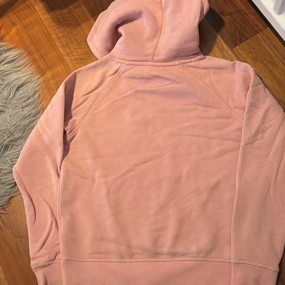Säljer en snygg rosa hoodie från GANT med vit logotyp på bröstet. Tröjan har en klassisk känguruficka och en bekväm huva. Perfekt för en avslappnad stil.. Neuletakit & Villapaidat.