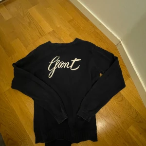 Mörkblå bomullströja, stickad från Gant - Snygg mörkblå tröja från Gant i 100% bomull. Den har en stilren design med Gant-loggan i vitt på framsidan skrivet med skrivstil . Perfekt för en avslappnad och trendig look. Kan tänka mig att diskutera priset!