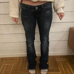 Mörkblå low waist jeans - Snygga mörkblå jeans med låg midja och dekorativa fickor. Midja: 27 Längd:32