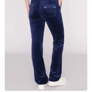 Mörkblå juicybyxor - Snygga mörkblå juicybyxor med snörning i midjan och raka ben. Byxorna har praktiska fickor bak med knappdetaljer. Perfekta för en avslappnad och stilren look. saknar metall grej på ena snöret se bild 3 en sån saknas (kom privat för egna bilder) ÄR ÄKTA O KÖPTA FÖR 1200