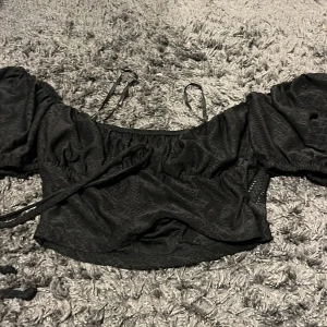 Svart offshoulder topp från SHEIN - Snygg svart offshoulder topp från SHEIN med puffiga ärmar och knytband. Perfekt för en trendig look. Tillverkad i ett lätt och bekvämt material.