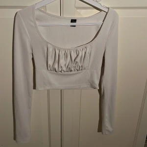 Vit ribbad topp  - Säljer en vit ribbad topp från Shein med långa ärmar och en snygg rynkad detalj framtill. Perfekt för en stilren look.