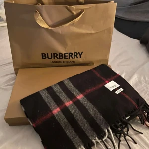 Svart rutig halsduk från Burberry - Säljer denna burberry halsduk för att jag använder den inte så mycket. Låda och påse fås med om de önskas, skriv gärna om frågor finns!