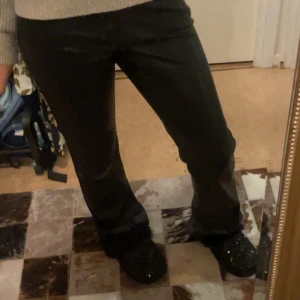 Svarta skinnbyxor - Snygga svarta skinnbyxor med en tight passform med bootcut. Perfekta för en trendig look. Byxorna har en hög midja, vilket ger en stilren siluett. Super bra skick. Storlek  38 men sitter bra på mig som brukar bära 34! dom är highwaist men jag brukar ha en stickad tröja över så man inte kan se eller bara vika ner!