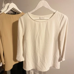 Vit blus från Vila - Säljer en stilren vit blus från Vila med trekvartsärm. Perfekt för både vardag och mer uppklädda tillfällen. Blusen har en rund halsringning och är tillverkad i ett mjukt material.