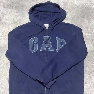 Mörkblå hoodie från GAP - Säljer en mörkblå hoodie från GAP. Kommer inte till användning längre så säljer vidare koftan. Den är  i mycket bra skick och originarie pris ligger runt 600kr                            Bara att skriva vid funderingar eller frågor. 