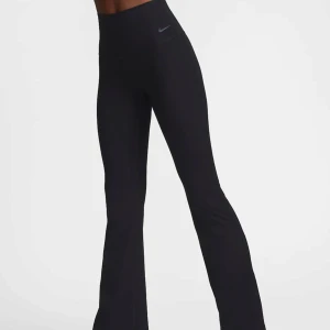 Utsvängda tights från Nike - Snygga svarta träningsbyxor från Nike med hög midja och bootcut-stil. Perfekta för träning eller en avslappnad dag. Byxorna har en diskret Nike-logga på höften. Som nya - inga täcken på användning 