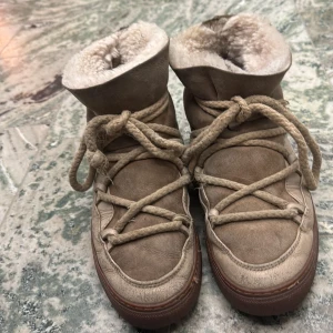 Inuikii skor beige - Säljer ett par beige boots från Inuikii med snörning och varmt pälsfoder. Perfekta för kalla dagar med sin robusta design och bekväma passform. Priset går att diskuteras