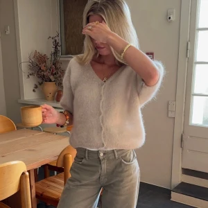 Beige stickad kofta - Mysig beige stickad kofta med kortärmad design och knappar framtill. 80% mohair och storlek xs/s. Nästan aldrig använd!