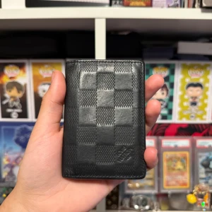 Louis Vuitton Infini Leather Pocket Organizer - Snygg svart plånbok från Louis Vuitton med klassiskt rutmönster. Tillverkad i skinn och har flera fack för kort. Perfekt för att hålla ordning på dina kort och kontanter.