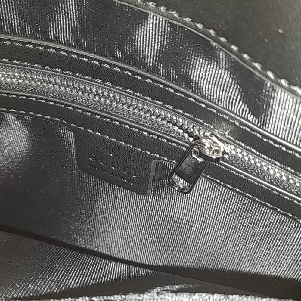 Snygg svart axelväska från Gucci med klassiskt GG-mönster. Väskan har en justerbar axelrem i rött och blått samt en praktisk dragkedja framtill. Perfekt för att bära dina nödvändigheter med stil. Den är helt oanvänd. Vid fler frågor tveka inte att höra av er🤝🏼🤩. Laukut & Käsilaukut.