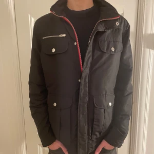 Svart Field jacka  - Tvär fet svart field jacka med röda detaljer från märket Jack&jones! Storlek M hör av er vid eventuella frågor! 